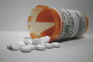 A pill bottle on its side spills white tablets out (photo)