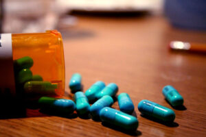 A bottle of blue pills overturned on a wooden table