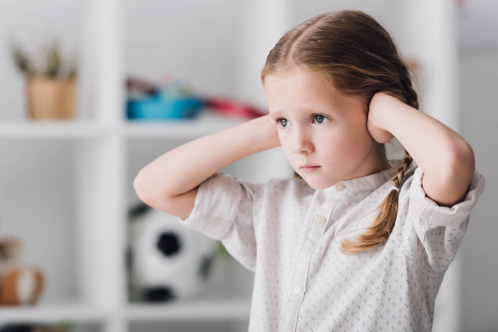 Photo of a white child covering ears with hands