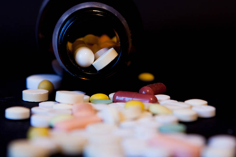 A bottle of spilled pills on black background.