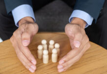 The Medicalization of the American Mind Close up of two hands circling a group of wooden figurines on a table