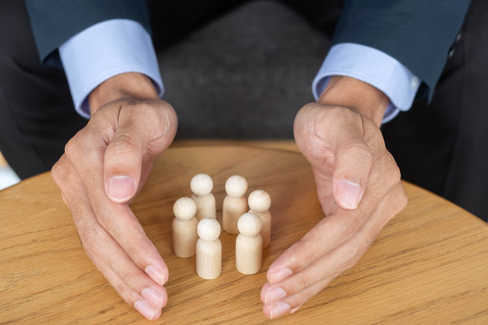 Close up of two hands circling a group of wooden figurines on a table