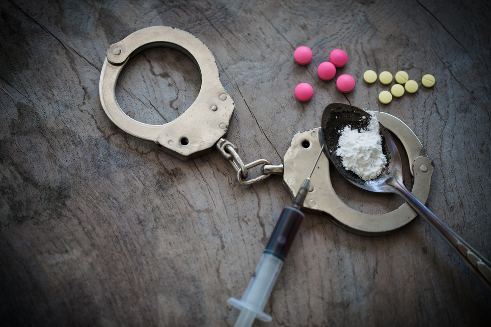 Drug syringe and cooked heroin on spoon and handcuffs . Concept - punishment for possession of narcotic drugs.