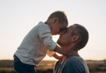 Positive Parenting Can Mitigate Effects of Childhood Stress, Study Reveals Father and son playing in the park at the sunset time. Family, trust, protecting, care, parenting, summer vacation concept