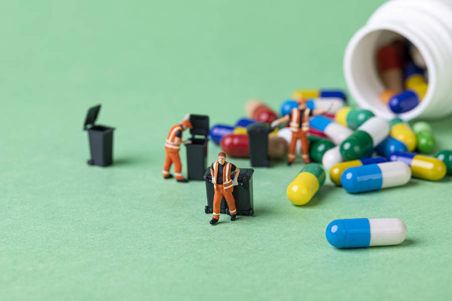 A selective focus shot of garbage collectors, trash cans, and giant pills