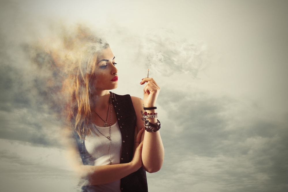 Woman smokes a cigarette in a cloud of smoke