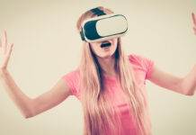 Why Failed Psychiatry Lives On: Its Industrial Complex, Politics, & Technology Worship A girl wearing virtual reality device over eyes looks startled with hands wide and mouth open