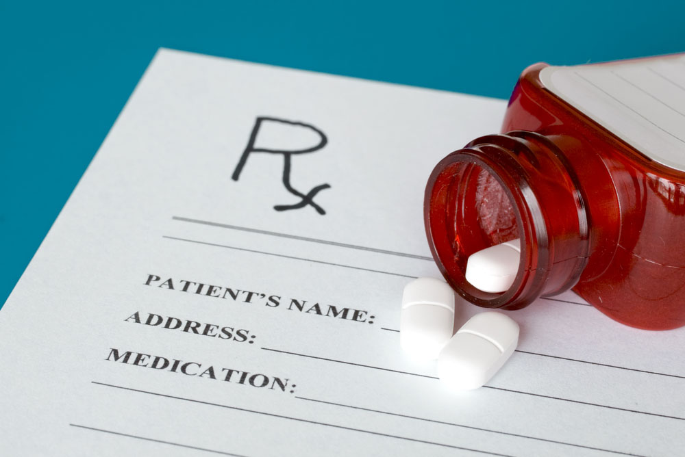 Prescription pills and red bottle on Rx form