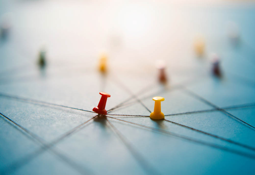 Macro photo of thumbtacks holding strings in a network on a blue background