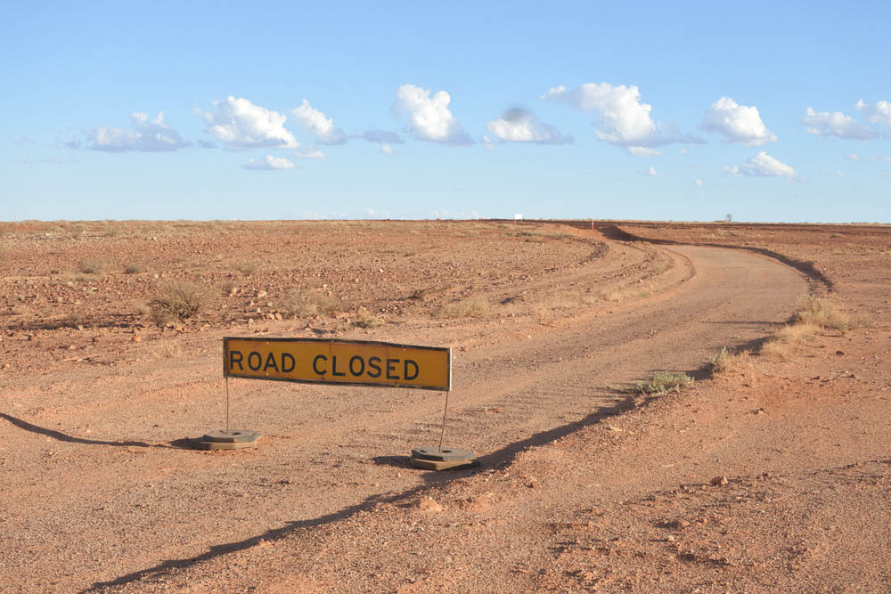 A sign in the desert reads "ROAD CLOSED"