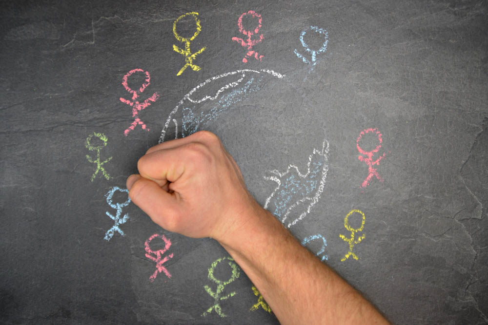 A hand erases a chalk drawing of the world surrounded by stick figures