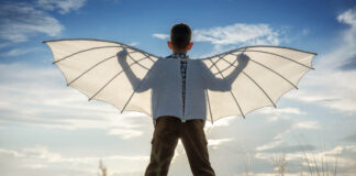Trying to Fly Above—An Example of Sequencity Boy with wings in the field in the afternoon against the blue sky