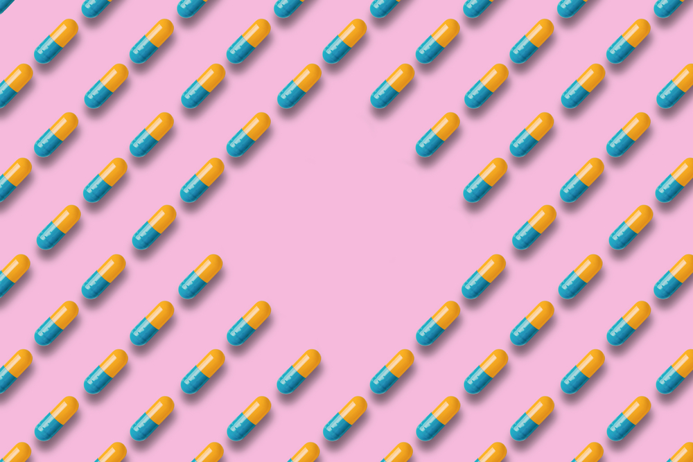 Pattern of blue and yellow pills or tablets on a pink background. concept of medicine, pharmacy and coronavirus. copy space