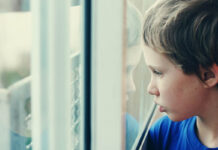 As a Psychologist, I’ve Seen Many Children Misdiagnosed as Autistic—It’s a Clinical Catastrophe Young boy looking through the window