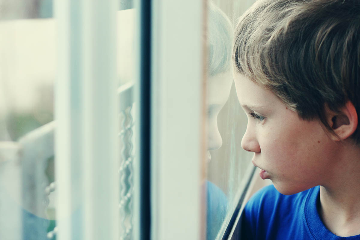 Young boy looking through the window