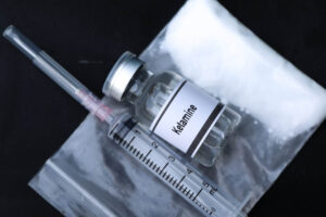 A syringe and a bottle labeled ketamine.