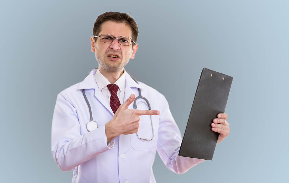 Doctor looking perplexed or angry pointing at a clipboard