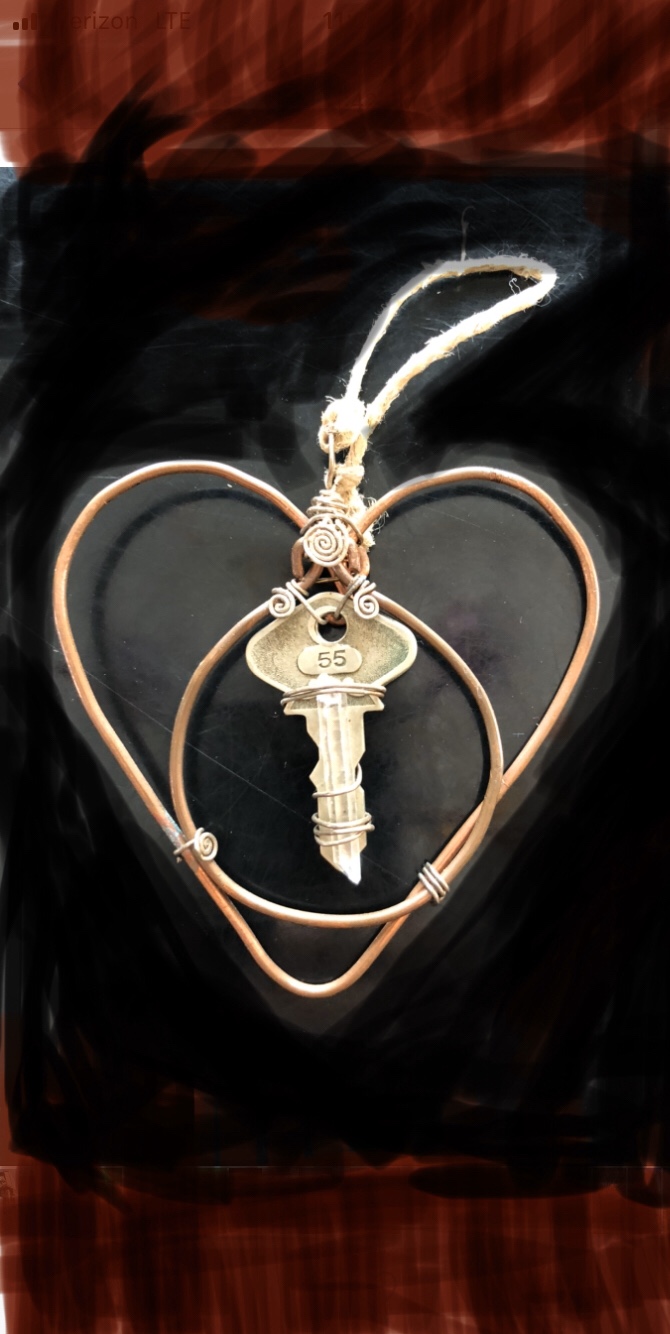 wire heart pendant form, made from a clothing hanger, with wire-wrapped key fastened at the center, black background with red at top and bottom