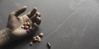 Close photo of a hand spilling pills on a floor