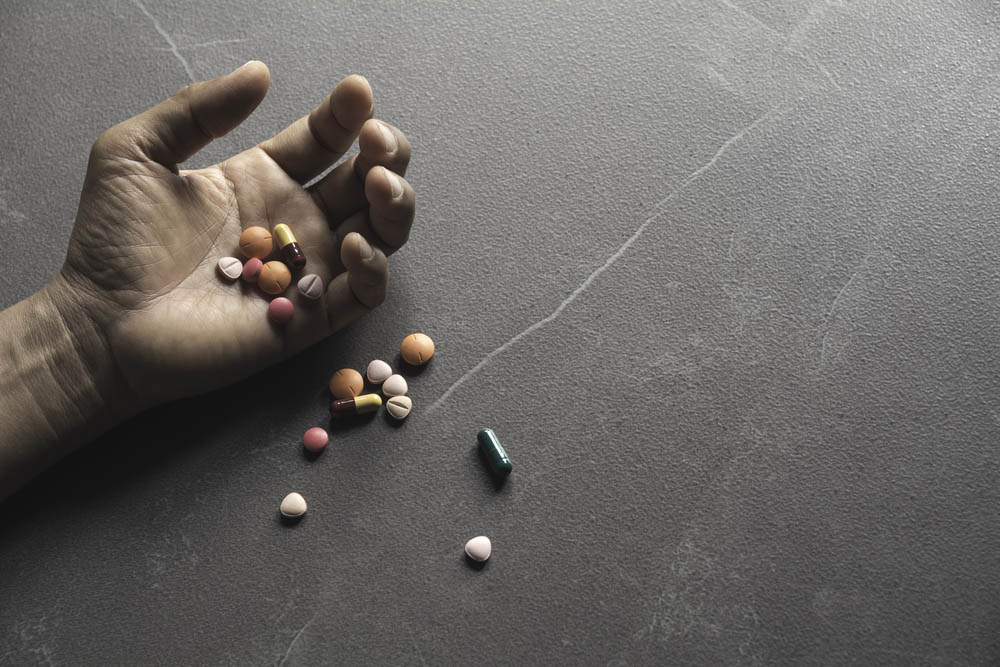 Close photo of a hand spilling pills on a floor