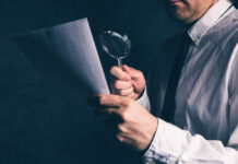 Many Results in Psychology and Medicine Are False Positives Close dark photo of man in suit holding magnifying glass up to paper
