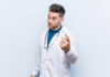 Doctors Are Not Trained to Think Critically Young handsome doctor man pointing with finger at you as if inviting come closer.