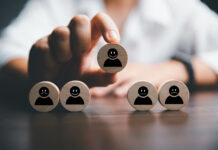 The Clinical, Social, and Cultural Harm of an Iatrogenic Psychiatry Stock photo. Wooden circles with simple faces. One smiling is picked up by fingers.