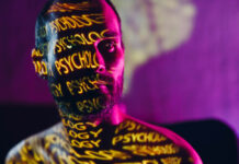 Mishiguene Young adult man with word Psychology on his face in the dark