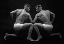 The Long-Disputed Science of Twin Studies Two similar looking men flexing muscles in black and white