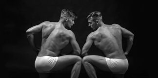 The Long-Disputed Science of Twin Studies Two similar looking men flexing muscles in black and white