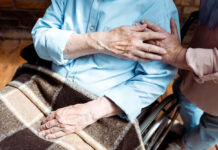Preventing Suicide Among Older Adults Older adult sitting with a blanket in lap, holding the hand of someone else out of frame