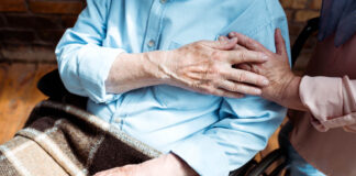 Preventing Suicide Among Older Adults Older adult sitting with a blanket in lap, holding the hand of someone else out of frame