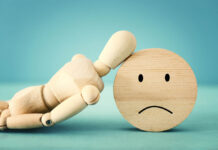 The Iatrogenic Gaze: How We Forgot That Psychiatry Could Be Harmful art mannequin leaning on a sad face wood block