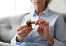 Poor Risk/Benefit Ratio for Antidepressants for Pain in Older Adults Seated older woman (face out of frame) holding pill bottle to read the label