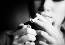 Smoke ‘Em if You Got ‘Em: Rethinking Smoking as a Trauma Response B&W photo of a young woman smoking. Close-up on the cigarette being lit by a lighter; her face is out of focus