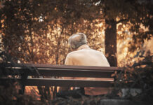 I Accuse Psychiatry of Murder senior man sitting alone. Lonely gray haired man on a bench in fall season