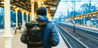 Exile: My Cure for Psychosis Train Station in Sopot, Poland, Europe. Attractive man waiting at the train station. Thinking about trip, with backpack. Travel photography. tourist with backpack stand on railway station platform.