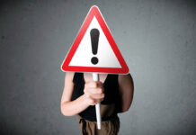 Mental Illness Prophesies Society’s Spiritual Sickness Stock image of a person holding a warning sign in front of their face.