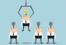 Managing Nonconformity: Lessons from Quality Vector illustration of businessmen on an assembly line with burned out light bulbs on their heads; one is being picked up by a robotic arm and has a lit lightbulb.