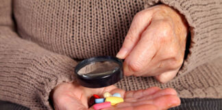 Psychiatric Drugs “A Crude Form of Chemical Restraint” Closeup of pills in hand, a magnifying glass