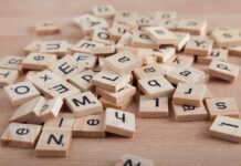 Pile of Scrabble letter blocks on wood background.