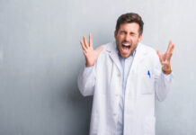 Stock photo. Man in lab coat appears to scream in anger.