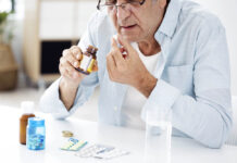 An elderly man takes a pill