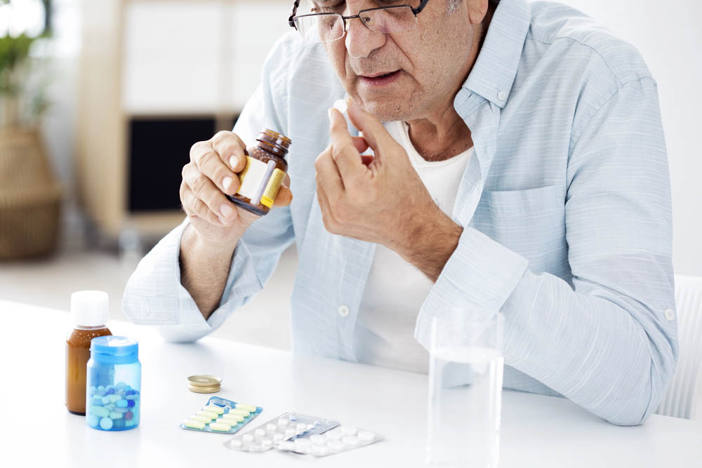 An elderly man takes a pill