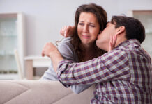 A woman looks distressed while a man kisses her