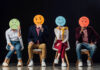 Photo of people holding round hand-drawn faces over their own faces, each depicting an emotion