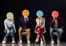 Photo of people holding round hand-drawn faces over their own faces, each depicting an emotion
