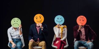 Photo of people holding round hand-drawn faces over their own faces, each depicting an emotion