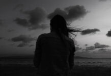 Alone woman at the beach one twilight time looking out to sea