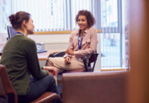 Female College Student Meeting With Campus Counselor Discussing Mental Health Issues